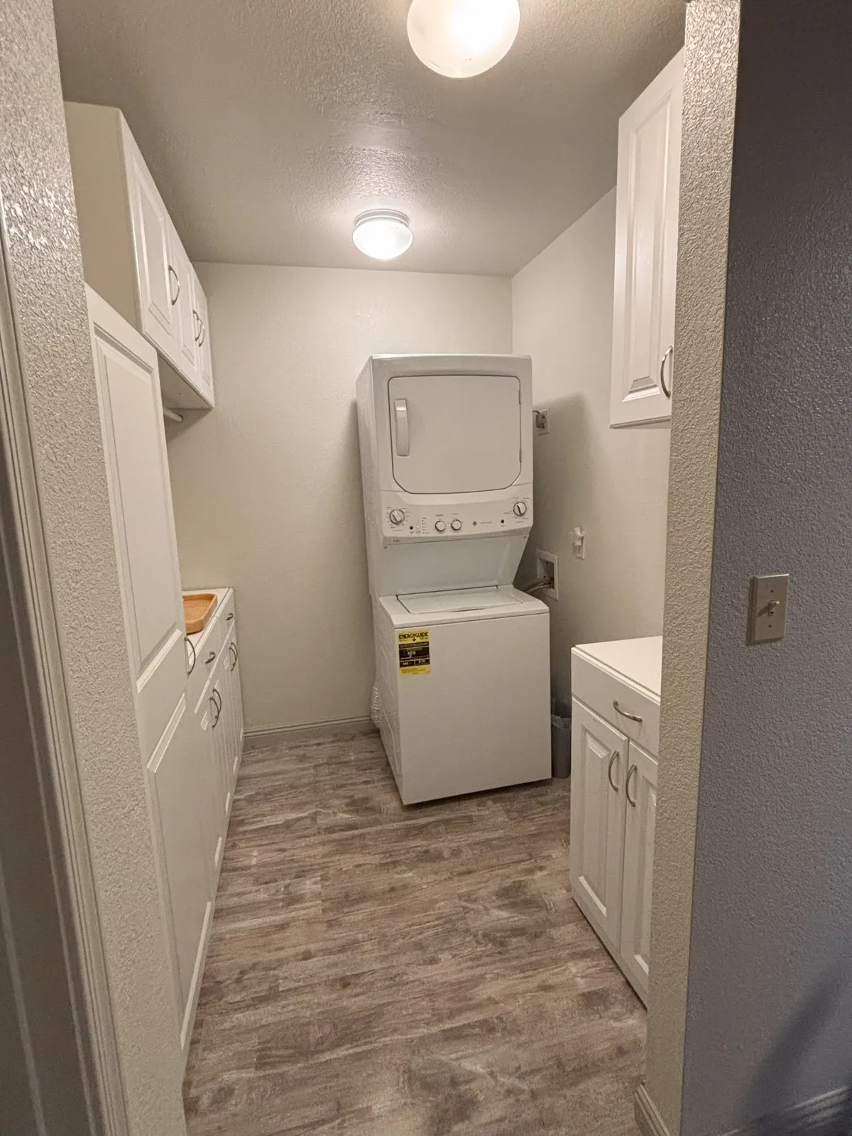 A practical laundry area featuring a washer and dryer, white cabinetry, and light-colored flooring. The neat, organized setup emphasizes the home's practical amenities and the ease with which guests can care for their winter gear after outdoor activities.