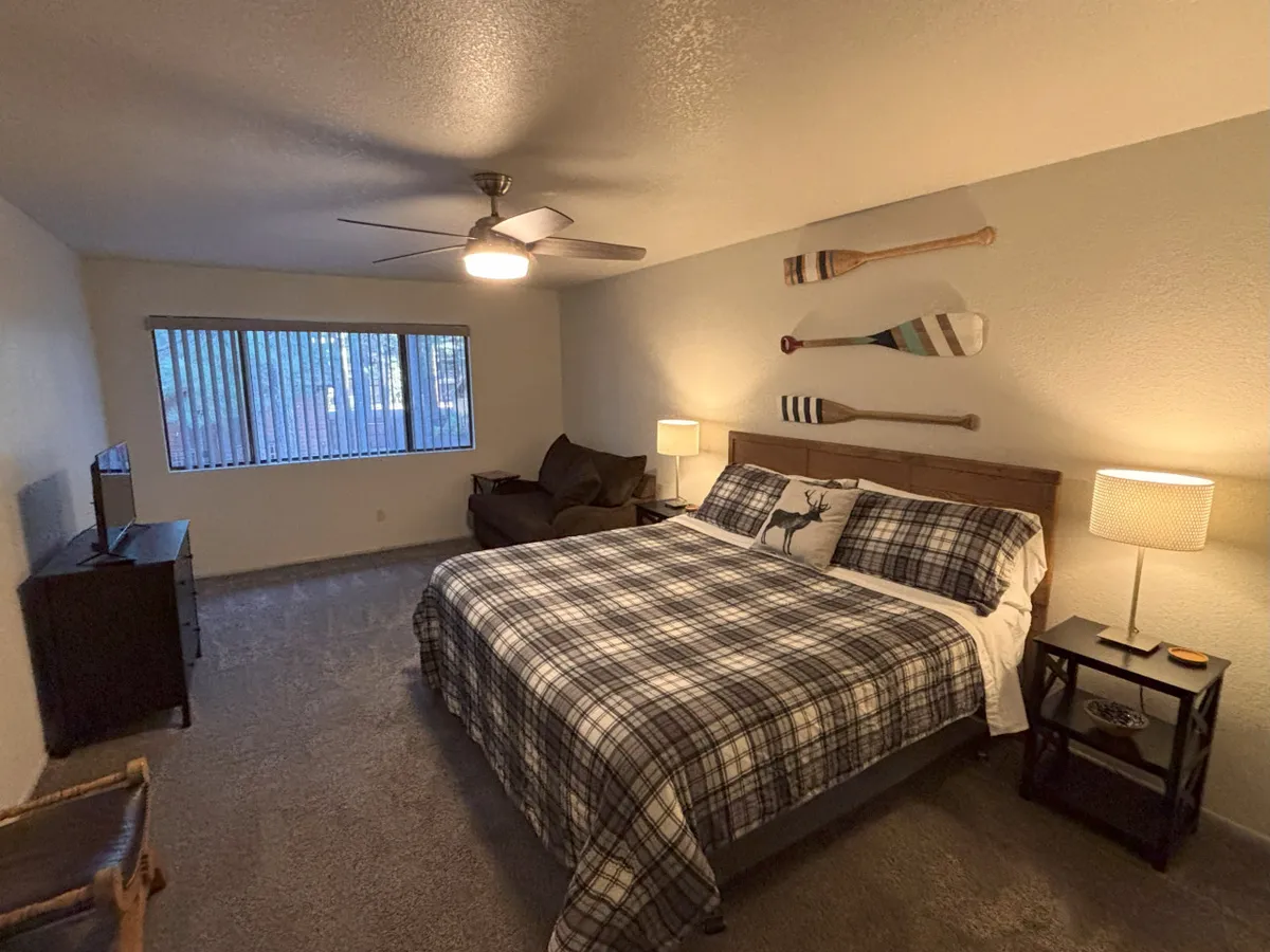 A welcoming bedroom with cozy plaid bedding, decorative oars on the wall, stylish lighting fixtures, and a television. The overall ambiance is comfortable and inviting, perfect for relaxation and unwinding after a long day.